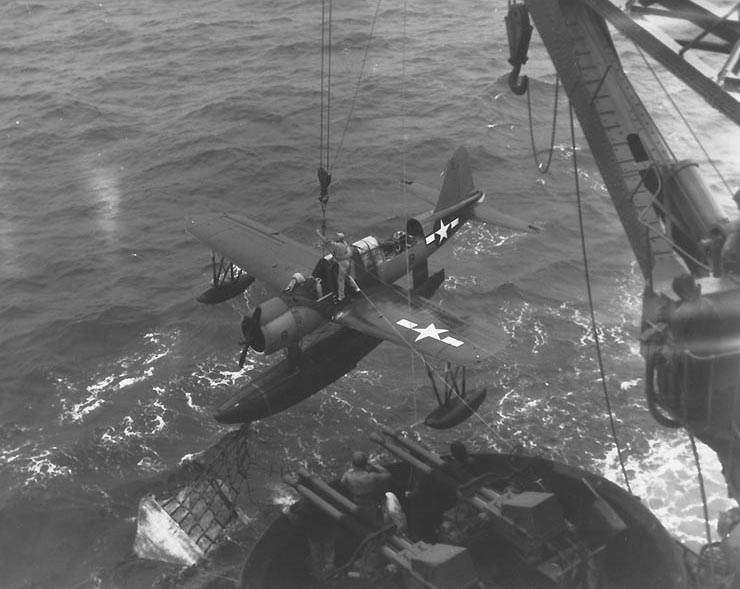 os2u-kingfisher-aircraft-being-recovered-by-battleship-uss-texas-off-iwo-jima-at-1700-on-16-feb-1945-note-netting-of-recovery-sled-hooked-on-pontoons-recovery-hook